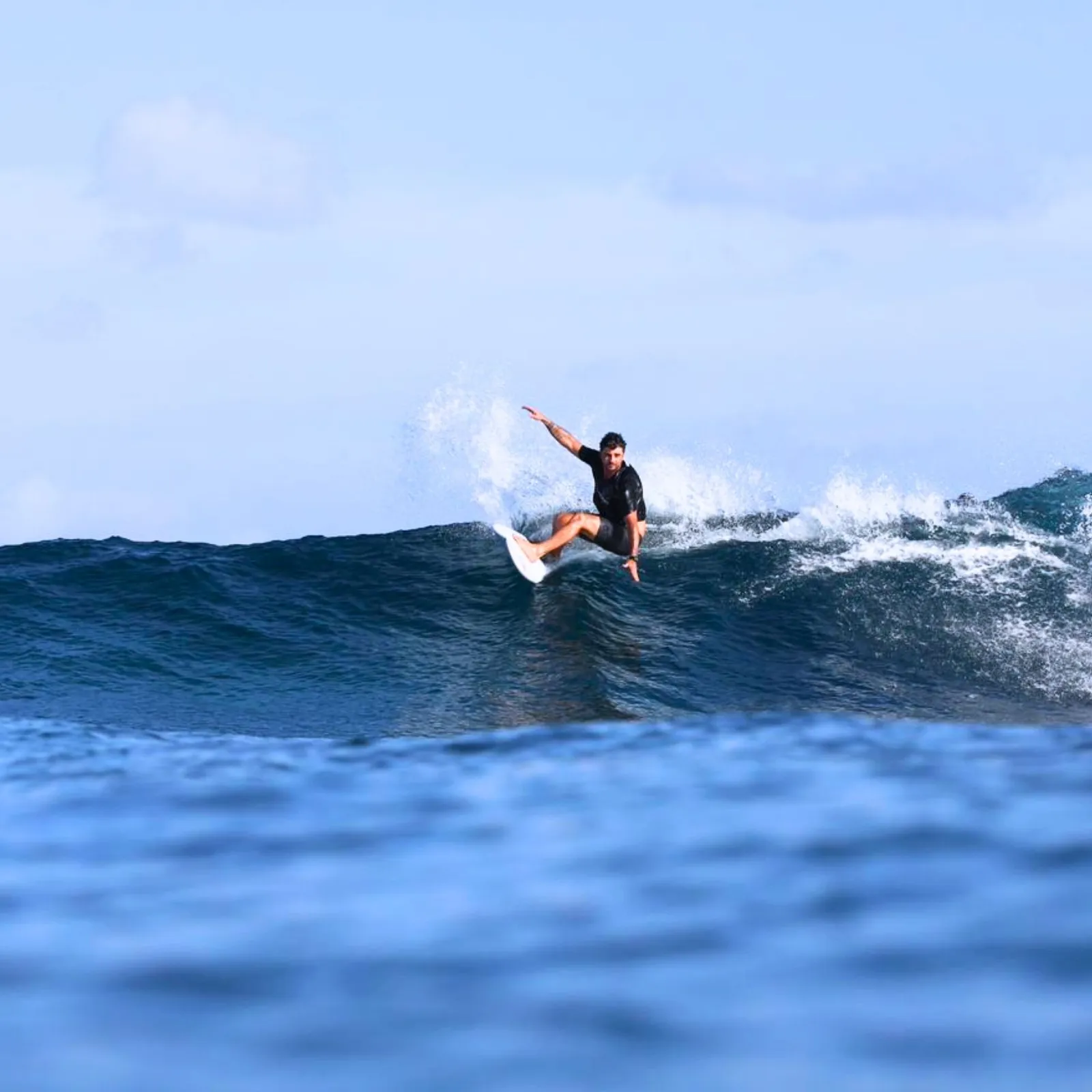 Surfista em onda cristalina nas Maldivas
