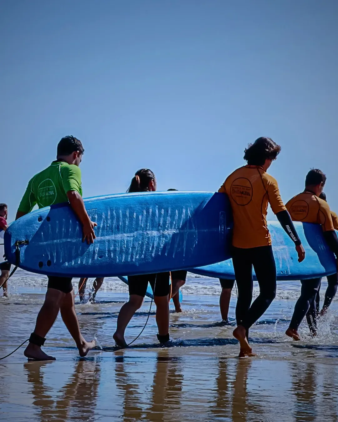 Turma de iniciantes levando as pranchas para o mar em Garopaba